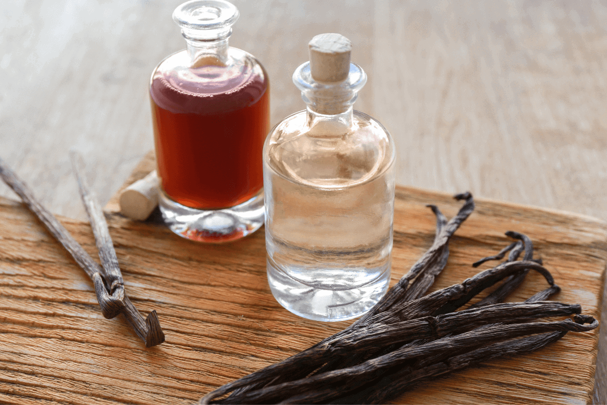 how to make vanilla extract banner image of vanilla beans on a cutting board next to alcohol and a bottle of vanilla extract with a knife for cutting vanilla beans